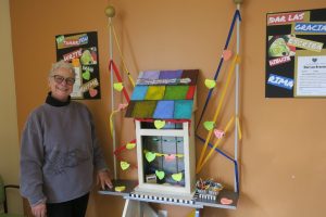 photo of Roberta standing in front of her art project in the Kennett Square waiting room.