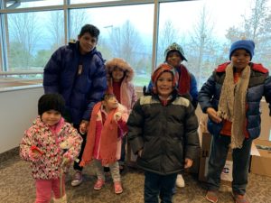 Six children of different ages, backgrounds, and abilities stand in the lobby are of LCH West Grove with their new coats.