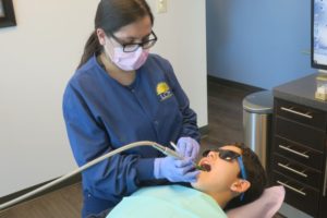 Dental assistant cleans the teeth of a child